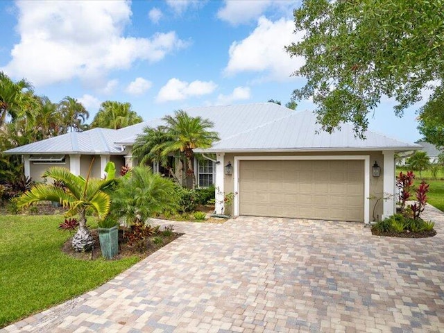 ranch-style home featuring an attached garage, a front lawn, driveway, and stucco siding