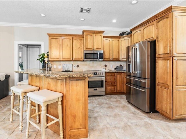kitchen featuring visible vents, light stone counters, ornamental molding, a breakfast bar, and stainless steel appliances