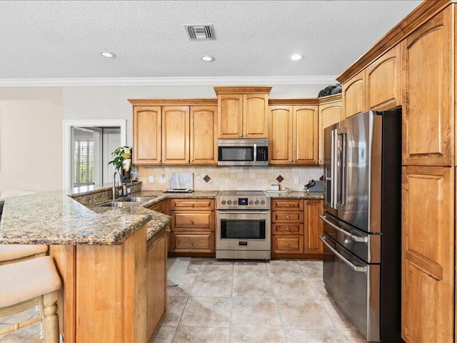 kitchen featuring visible vents, crown molding, a peninsula, a sink, and appliances with stainless steel finishes