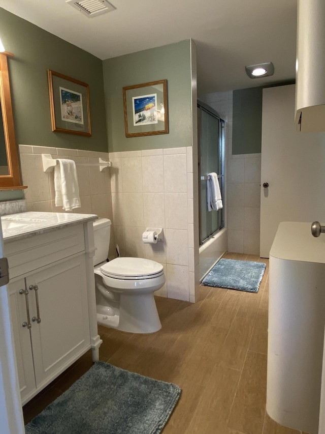 7 Royal Palm Way Unit 202, Boca Raton, FL 33432 - bathroom featuring tile walls, a shower with shower door, vanity, wood finished floors, and a wainscoted wall