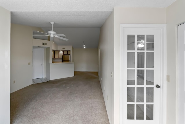 unfurnished living room with carpet flooring, ceiling fan, vaulted ceiling, and visible vents