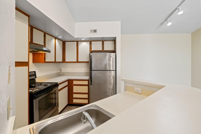 kitchen featuring under cabinet range hood, appliances with stainless steel finishes, light countertops, a sink, and visible vents