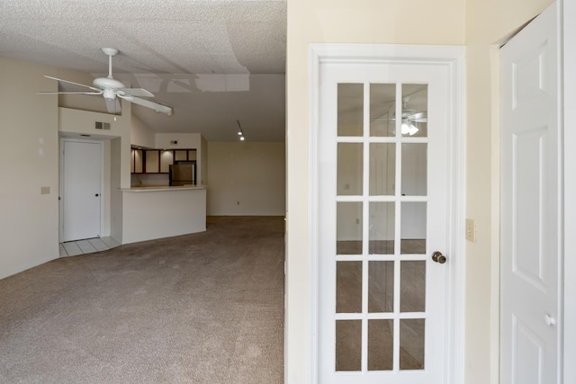 interior space with a ceiling fan, visible vents, carpet, and a textured ceiling