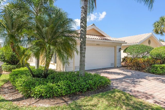view of front of home with stucco siding, an attached garage, decorative driveway, and a tiled roof