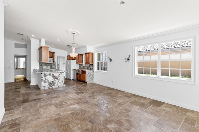unfurnished living room featuring crown molding, baseboards, an inviting chandelier, and stone tile flooring