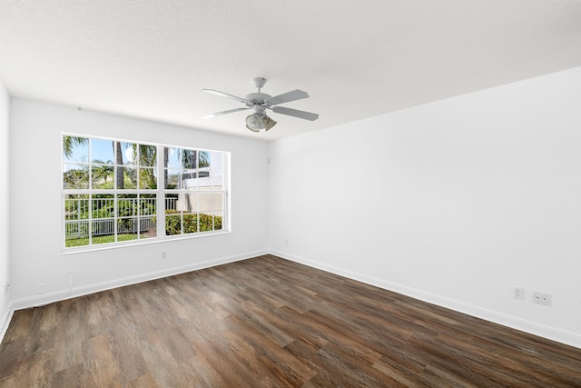 empty room with baseboards, a ceiling fan, and dark wood-style flooring