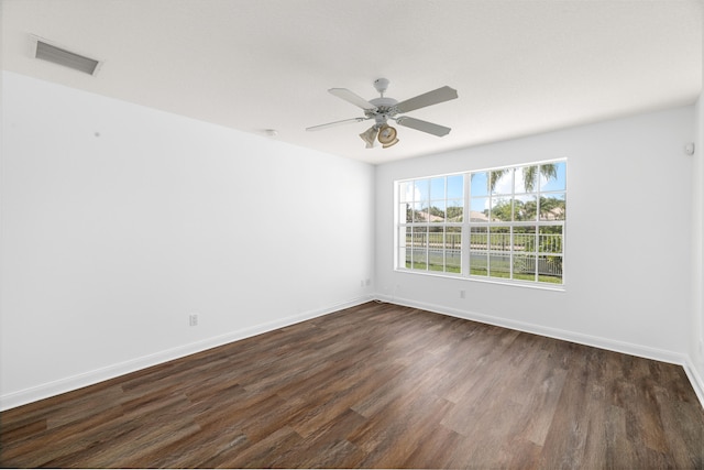 empty room featuring visible vents, dark wood-style flooring, ceiling fan, and baseboards