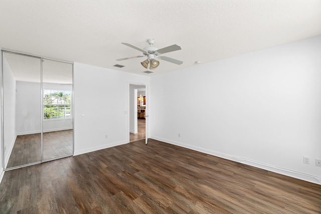 unfurnished bedroom featuring baseboards, ceiling fan, a closet, and dark wood-style flooring