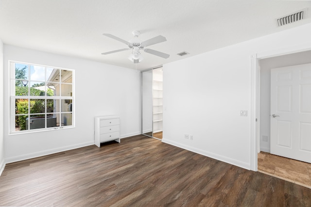 unfurnished bedroom with baseboards, a ceiling fan, wood finished floors, and visible vents