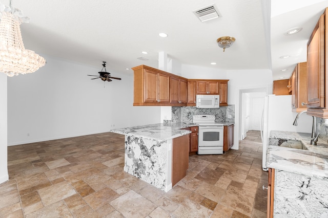 kitchen with visible vents, ceiling fan with notable chandelier, a peninsula, stone tile flooring, and white appliances