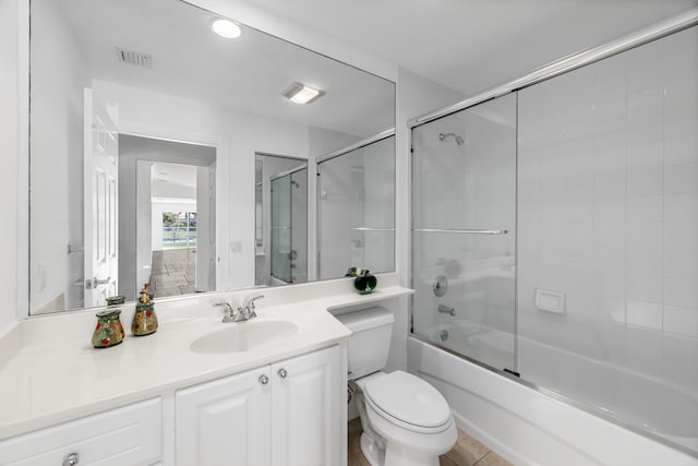 bathroom featuring visible vents, bath / shower combo with glass door, toilet, and vanity
