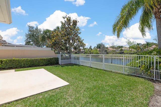 view of yard with a fenced backyard, a water view, and a patio area