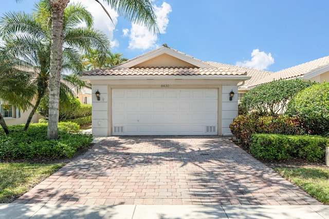 view of front of house with a garage, stucco siding, driveway, and a tile roof