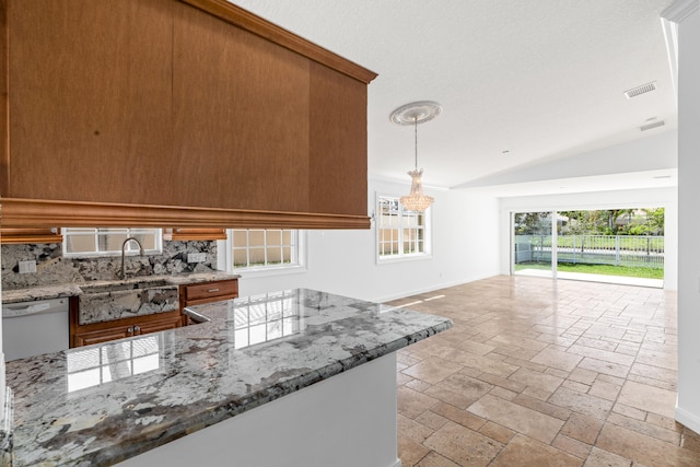 kitchen with brown cabinetry, visible vents, vaulted ceiling, dishwasher, and a sink