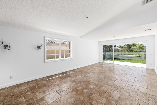 spare room with stone tile floors, a textured ceiling, and visible vents