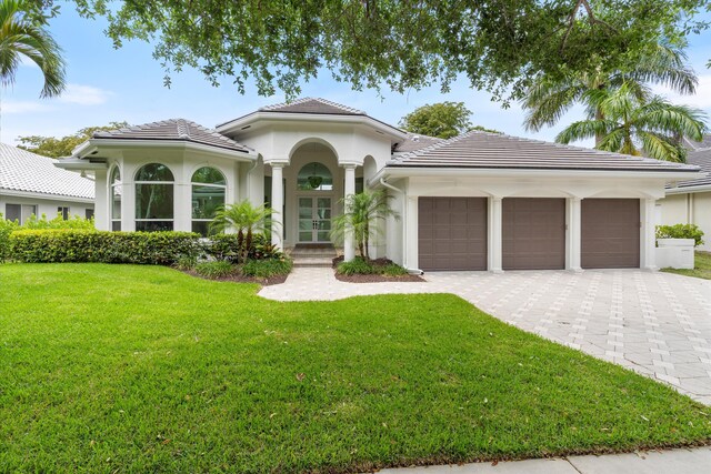 6247 NW 33rd Ave, Boca Raton, FL 33496 - mediterranean / spanish house with decorative driveway, french doors, an attached garage, a front yard, and stucco siding