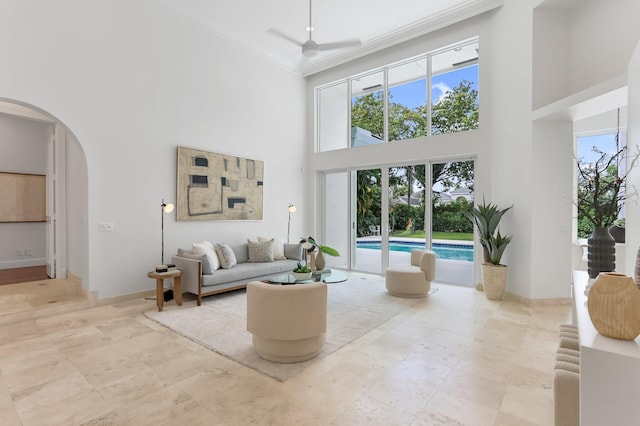 6247 NW 33rd Ave, Boca Raton, FL 33496 - living room featuring baseboards, a towering ceiling, arched walkways, and crown molding