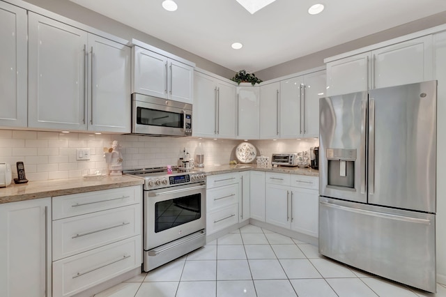 kitchen featuring white cabinetry, light tile patterned flooring, appliances with stainless steel finishes, and decorative backsplash