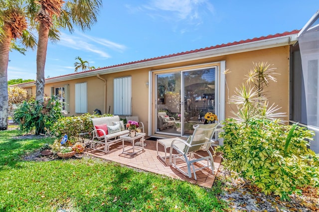 rear view of property with a tile roof, a patio, a lawn, and stucco siding