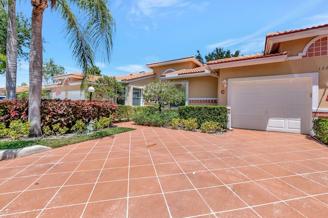 mediterranean / spanish home featuring stucco siding, an attached garage, and a tile roof