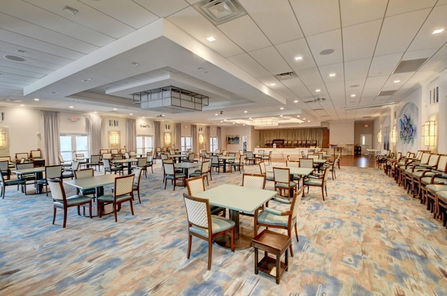 dining room with light colored carpet, a raised ceiling, and visible vents