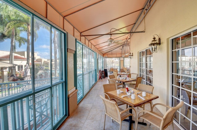 sunroom / solarium featuring a ceiling fan, high vaulted ceiling, and outdoor dining area