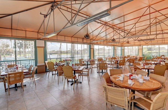 dining area with high vaulted ceiling and a water view