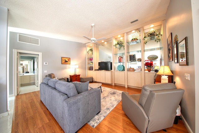 living area featuring a textured ceiling, visible vents, wood finished floors, and a ceiling fan