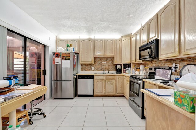 kitchen featuring light brown cabinetry, appliances with stainless steel finishes, backsplash, and light countertops