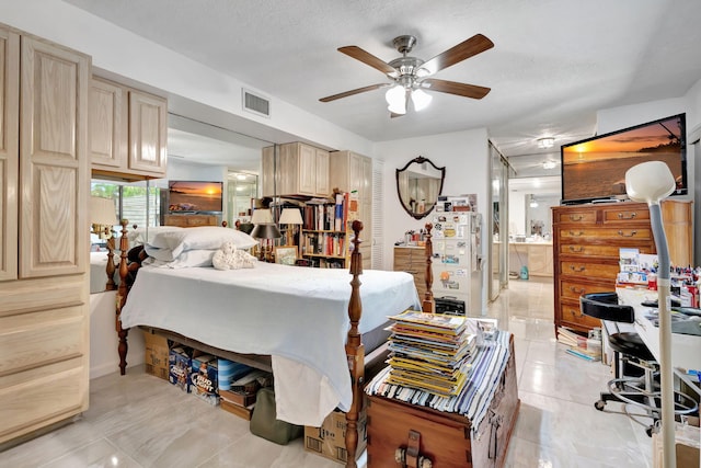 bedroom with freestanding refrigerator, ceiling fan, visible vents, and ensuite bathroom