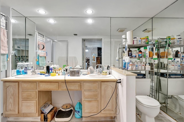 full bath featuring double vanity, toilet, recessed lighting, and a sink