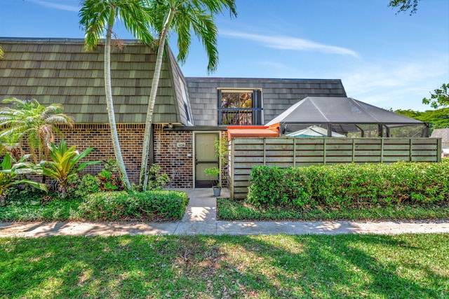 property entrance with brick siding, a lawn, and mansard roof