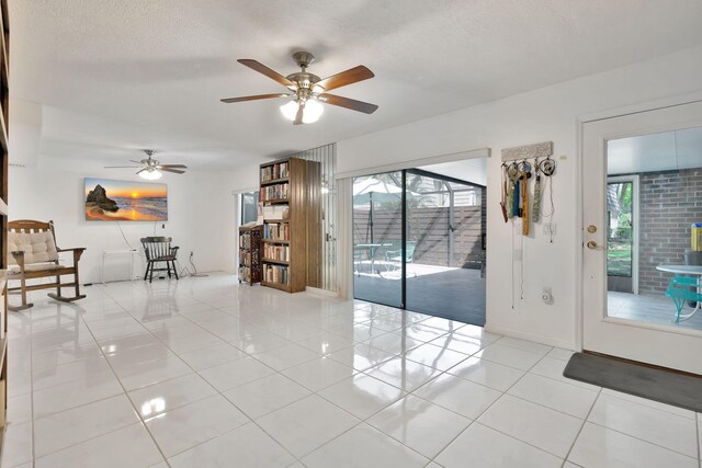 empty room featuring baseboards, a textured ceiling, ceiling fan, and light tile patterned flooring