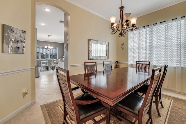 dining room featuring arched walkways, a chandelier, light tile patterned floors, and crown molding