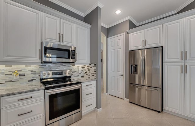 kitchen with decorative backsplash, appliances with stainless steel finishes, white cabinetry, and light tile patterned floors
