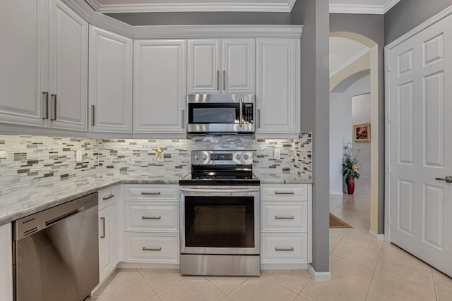 kitchen featuring arched walkways, ornamental molding, stainless steel appliances, and light tile patterned floors