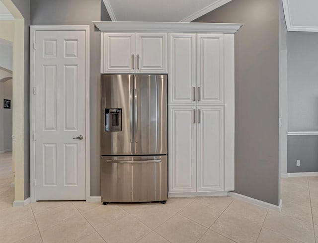 kitchen featuring arched walkways, stainless steel fridge, ornamental molding, and light tile patterned flooring