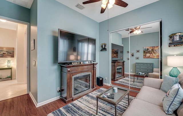 living room with baseboards, visible vents, wood finished floors, ceiling fan, and a fireplace