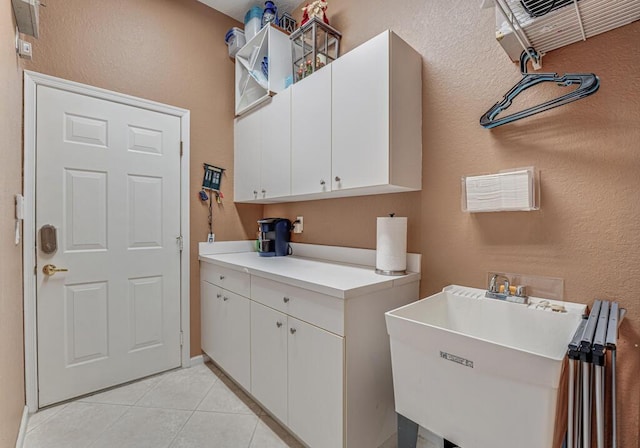 washroom with light tile patterned flooring, a textured wall, and a sink