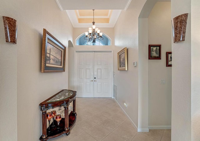 entryway with an inviting chandelier, light tile patterned flooring, arched walkways, crown molding, and baseboards