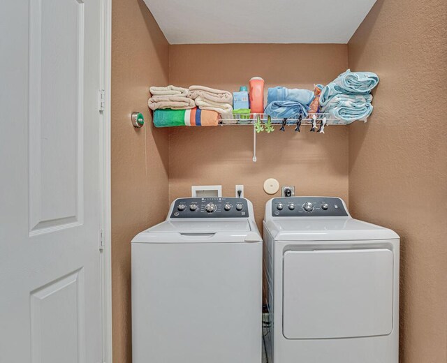 washroom featuring washer and dryer, a textured wall, and laundry area