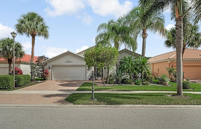 view of front of house featuring stucco siding, an attached garage, a front lawn, and decorative driveway
