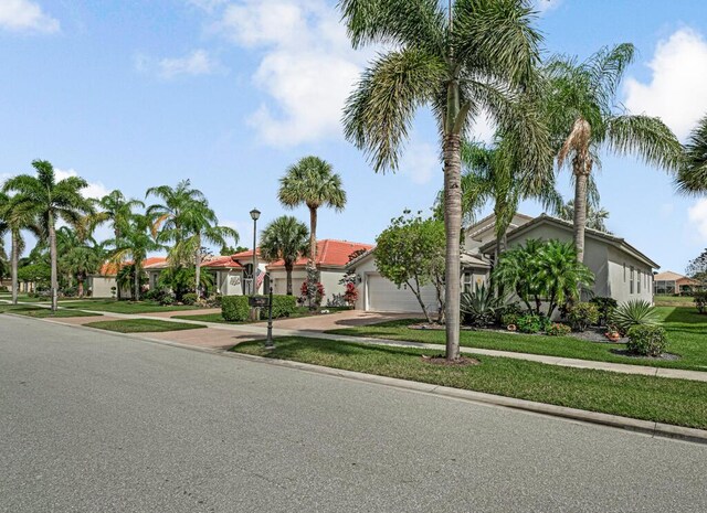 mediterranean / spanish-style home with a front lawn, driveway, an attached garage, stucco siding, and a residential view