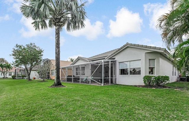 back of house featuring central AC, glass enclosure, a lawn, a tiled roof, and stucco siding