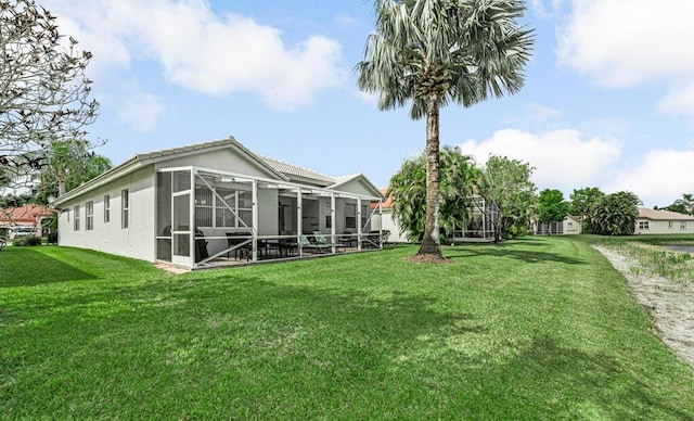 back of house with a lawn, a lanai, and stucco siding