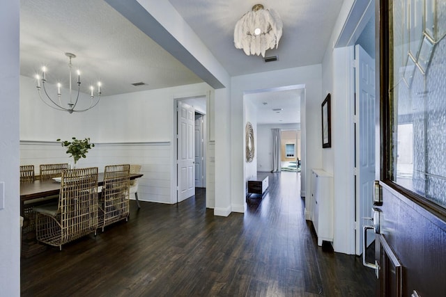 foyer entrance with a notable chandelier, dark wood-style floors, and visible vents