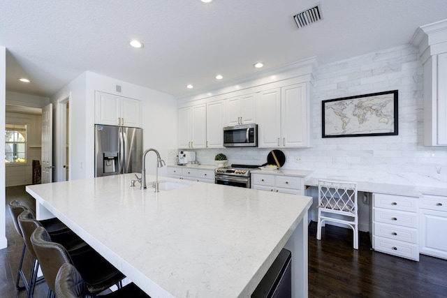 kitchen with a sink, appliances with stainless steel finishes, tasteful backsplash, and visible vents