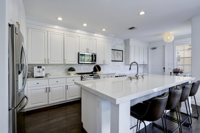 kitchen featuring decorative backsplash, appliances with stainless steel finishes, a sink, dark wood-style floors, and white cabinetry