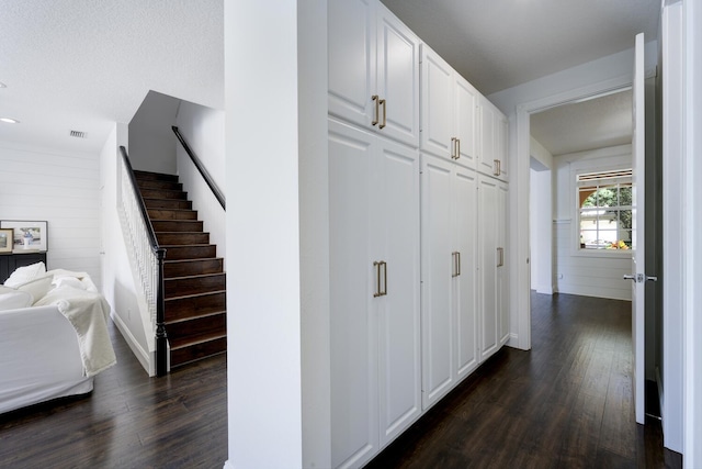 hallway featuring baseboards, visible vents, dark wood-style floors, and stairs