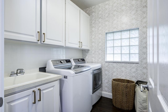 laundry area featuring dark wood-style flooring, cabinet space, a sink, wallpapered walls, and washer and dryer